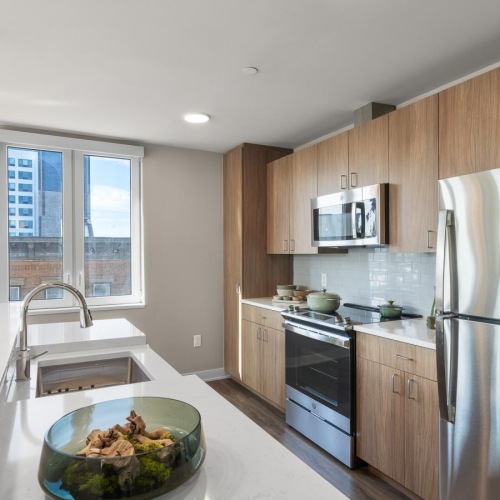 Modern kitchen with wood cabinets at The Grand North Bergen apartments for rent.